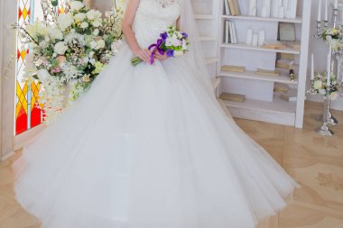 Gelin bir gelinlik bir buket ile el oturuyor