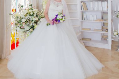 Gelin bir gelinlik bir buket ile el oturuyor