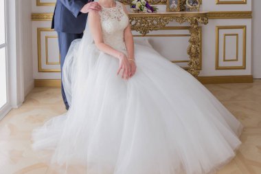 damat gelini parlak bir odada yanında duruyor