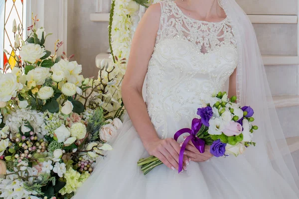 Η νύφη κάθεται σε ένα γαμήλιο φόρεμα με μια ανθοδέσμη στο χέρι — Φωτογραφία Αρχείου