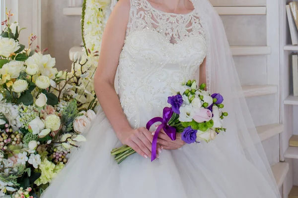 La mariée est assise dans une robe de mariée avec un bouquet à la main — Photo