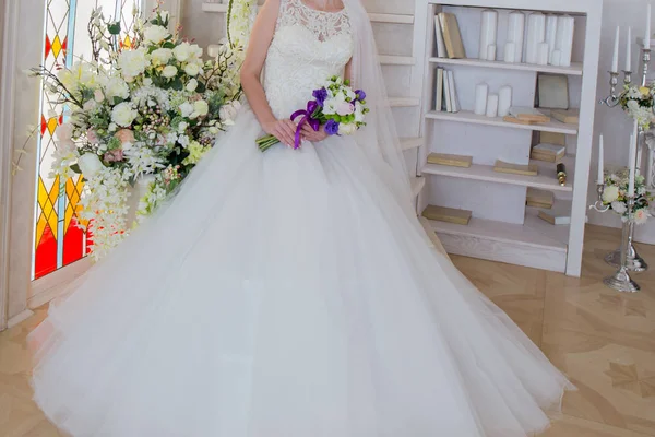 Die Braut sitzt in einem Brautkleid mit einem Strauß in der Hand — Stockfoto