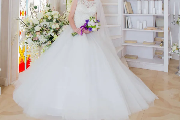 The bride is sitting in a wedding dress with a bouquet in hand — Stock Photo, Image