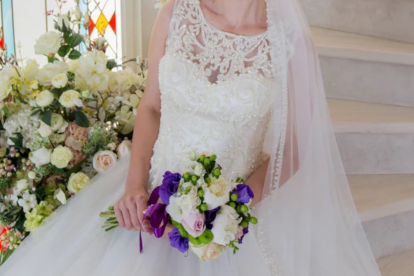 Невеста сидит в свадебном платье с букетом в руке — стоковое фото