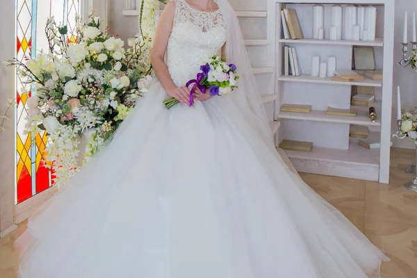 Nevěsta ve svatebních šatech s kyticí v ruce sedí — Stock fotografie
