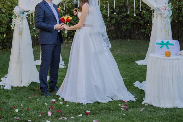 Noiva e noivo perto do arco da cerimônia de casamento — Fotografia de Stock