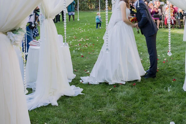 Novia y novio cerca del arco de la ceremonia de la boda — Foto de Stock