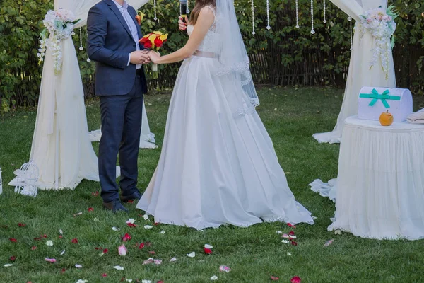Noiva e noivo perto do arco da cerimônia de casamento — Fotografia de Stock