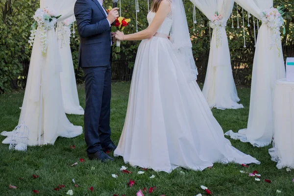 Novia y novio cerca del arco de la ceremonia de la boda — Foto de Stock