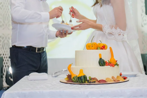 Bruid en bruidegom knippen de bruidstaart op tafel — Stockfoto