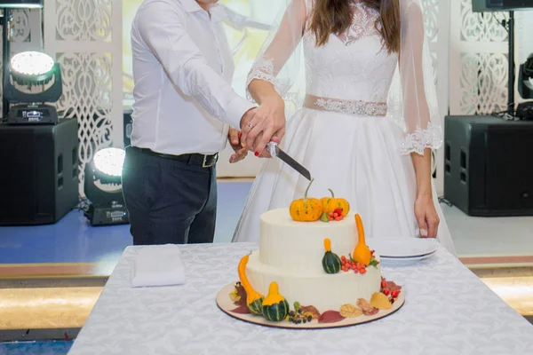 Bruid en bruidegom knippen de bruidstaart op tafel — Stockfoto