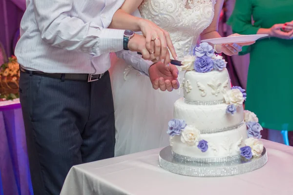 Bruden och brudgummen skär bröllopstårta med en kniv — Stockfoto