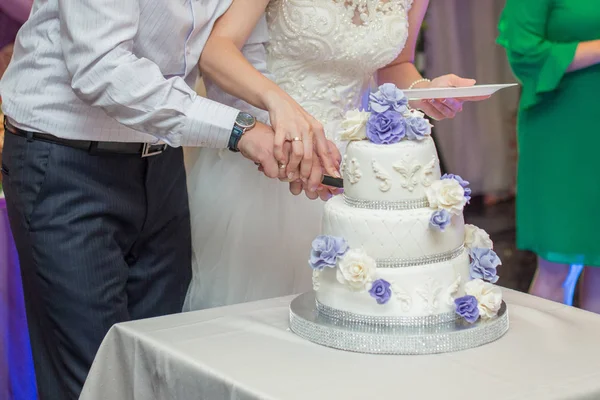 Das Brautpaar schneidet die Hochzeitstorte mit einem Messer an — Stockfoto