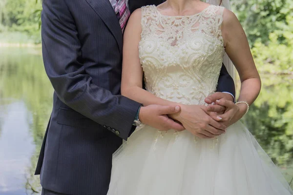 Bruden och brudgummen utmärker kramas i trädgården — Stockfoto
