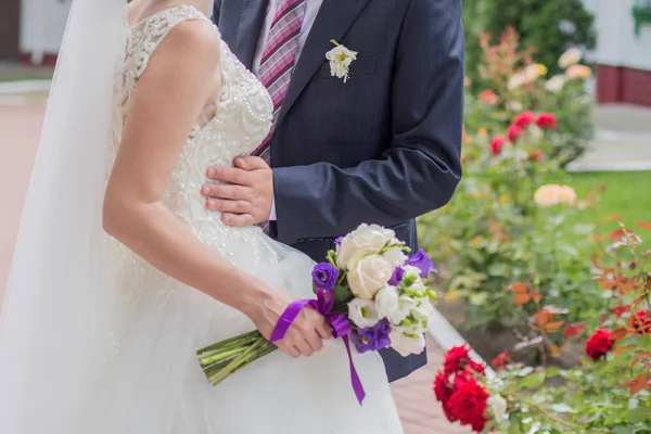 Bride and groom hold hands in the park — Stock Photo, Image