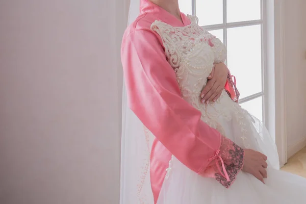 Mariée dans un peignoir près de sa robe de mariée — Photo