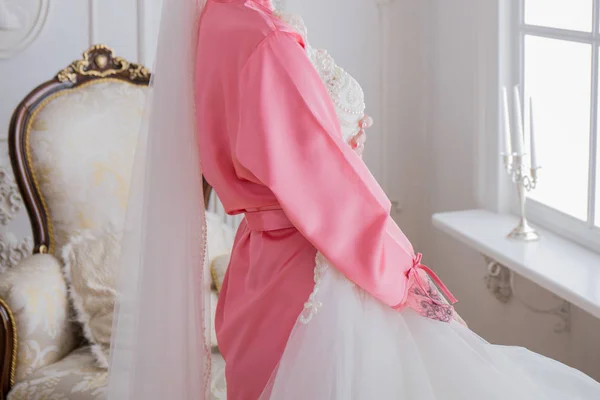 Bride in a bathrobe near her wedding dress — Stock Photo, Image