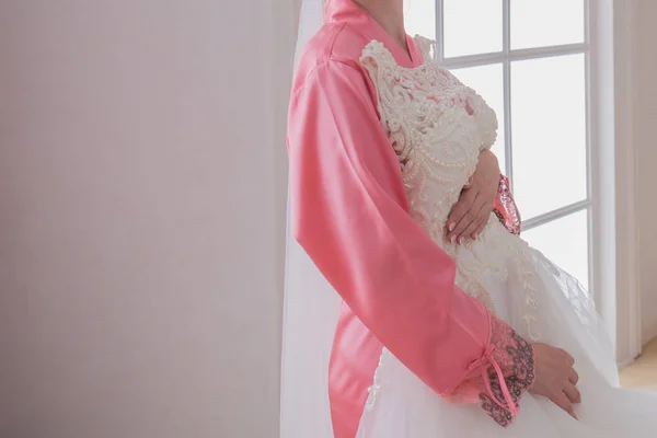 Braut im Bademantel neben ihrem Brautkleid — Stockfoto