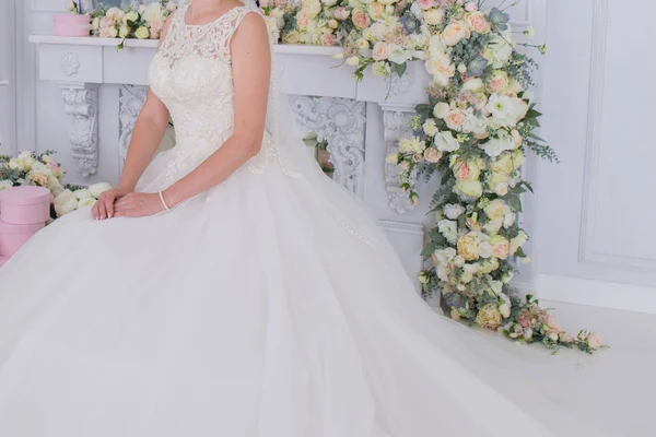Bruid in de sluier en bloemen in de buurt van de witte muur — Stockfoto