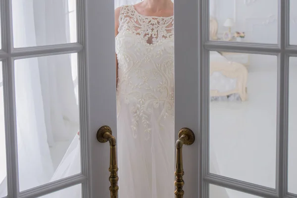 Νύφη στο γάμο φόρεμα στέκεται δίπλα στην πόρτα — Φωτογραφία Αρχείου