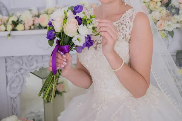 Bruid in de sluier en bloemen in de buurt van de witte muur — Stockfoto