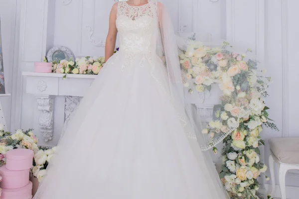 Braut in Schleier und Blumen in der Nähe der weißen Mauer — Stockfoto
