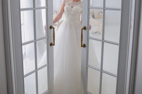 Novia en el vestido de novia está al lado de la puerta —  Fotos de Stock
