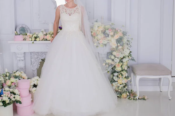 Braut in Schleier und Blumen in der Nähe der weißen Mauer — Stockfoto