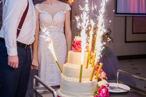 烟花在新婚蛋糕的背景上的新婚夫妇 — 图库照片