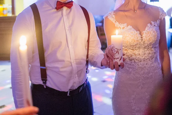Bride and groom hold a candle in hand — Stock Photo, Image
