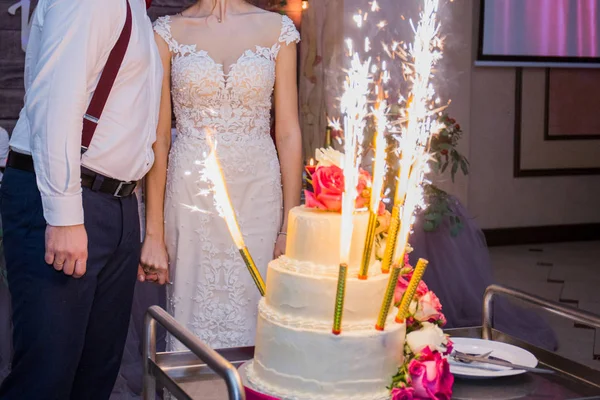 Fogos de artifício em um bolo de casamento no fundo dos recém-casados — Fotografia de Stock