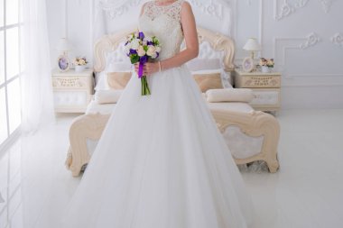 gelin düğün buket aydınlık bir salonda tutar.