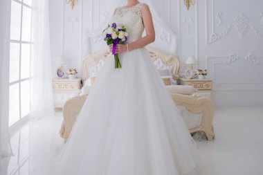 gelin düğün buket aydınlık bir salonda tutar.