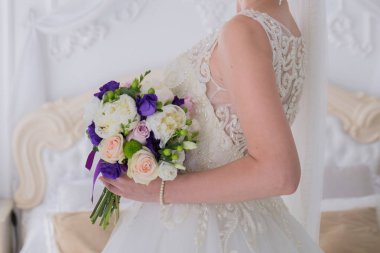 gelin düğün buket aydınlık bir salonda tutar.