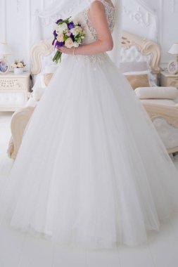 gelin düğün buket aydınlık bir salonda tutar.