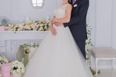 Gelin ve damat birlikte aydınlık bir salonda stand