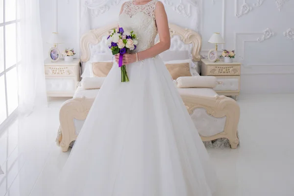Braut hält einen Hochzeitsstrauß in einem hellen Raum — Stockfoto