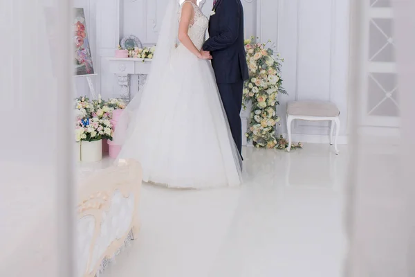Bruid en bruidegom staan samen in een lichte kamer — Stockfoto