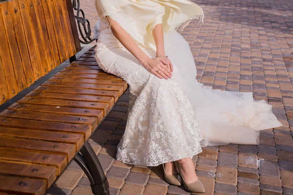 A noiva está sentada em um banco no parque — Fotografia de Stock