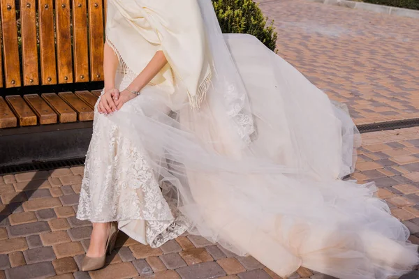 La mariée est assise sur un banc dans le parc — Photo