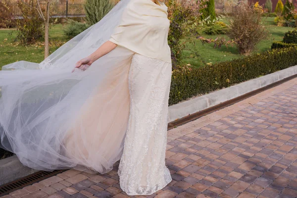 Невеста машет платьем на ветру в парке — стоковое фото