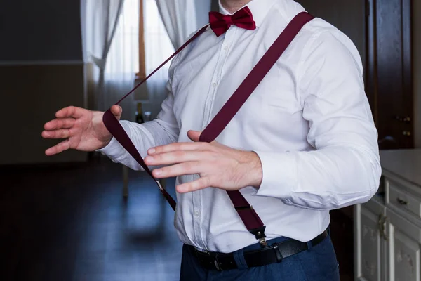 The groom holds his hands suspenders in a suit — Stock Photo, Image