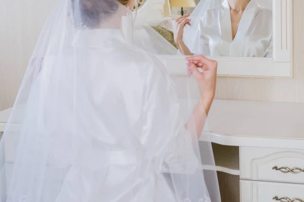 Невеста сидит рядом со столом в комнате в халате — стоковое фото