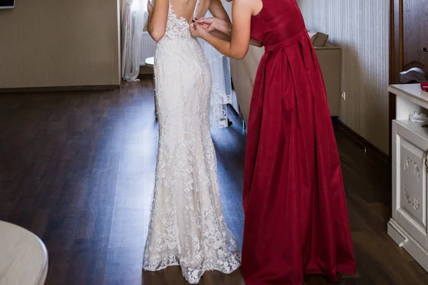 Girlfriend puts a wedding dress on bride — Stock Photo, Image