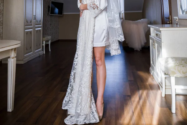 Bride in bathrobe holding wedding dress in hands — Stock Photo, Image