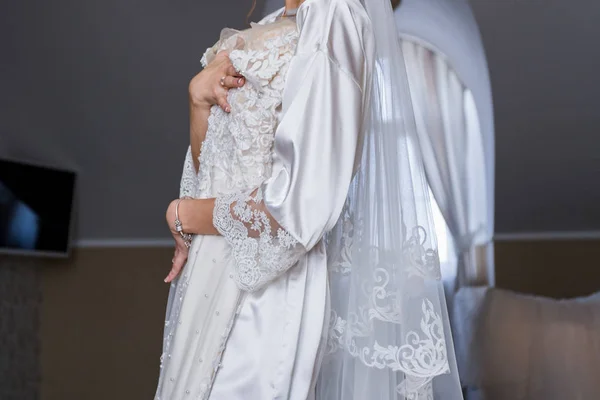 Bride in bathrobe holding wedding dress in hands — Stock Photo, Image