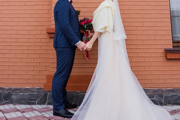 Mariée et marié se tiennent ensemble contre le mur de briques — Photo