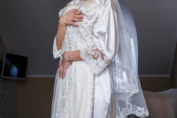Bride in bathrobe holding wedding dress in hands — Stock Photo, Image