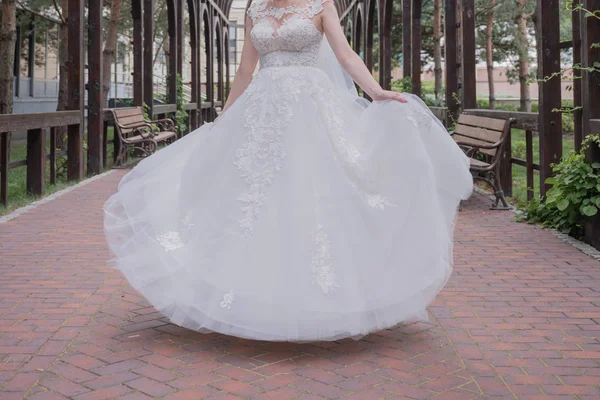 Bride in wedding dress whirls in the park — Stock Photo, Image