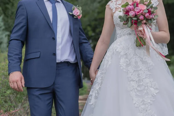 Noiva e noivo caminham juntos pela mão no parque — Fotografia de Stock